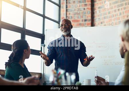 Homme d'affaires qui fait la présentation, la planification et la discussion dans une réunion, un séminaire ou une conférence de formation dans une salle de réunion au travail. Employés à l'écoute d'un responsable, en établissant des plans et en travaillant ensemble Banque D'Images