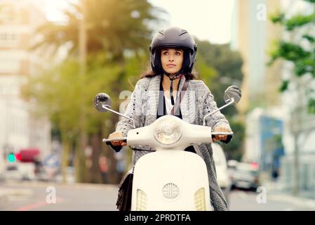 Soyez toujours attentif à l'endroit où chaque voyage mène. Une jeune femme attirante qui fait le tour de la ville à bord de son scooter. Banque D'Images