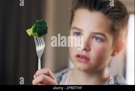 Si son vert doit être brut. Un jeune garçon refusant de manger son brocoli à la maison. Banque D'Images