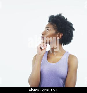 Penser hors de la boîte. Photo en studio d'une jeune femme attirante regardant vers le haut et se sentant réfléchie sur un fond gris. Banque D'Images