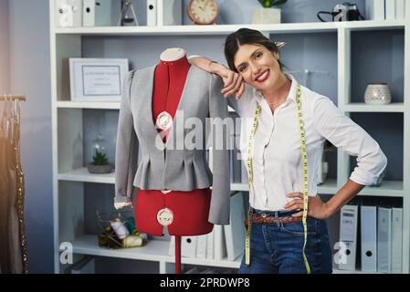 Sa ma fierté et ma joie. Portrait court d'un jeune designer de mode attrayant travaillant sur un mannequin dans son studio de design. Banque D'Images