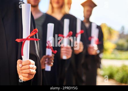 Nos billets pour changer le monde. Gros plan d'un groupe d'étudiants non reconnaissables détenant leur diplôme le jour de la remise des diplômes. Banque D'Images