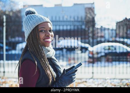 Il faisait froid mais j'ai eu le meilleur hotspot. Une belle jeune femme utilisant un téléphone mobile lors d'une journée enneigée en plein air. Banque D'Images