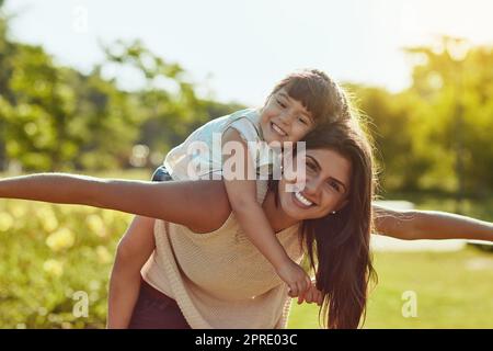 Maman a une quantité infinie d'amour à donner. Une adorable petite fille et sa mère appréciant une promenade de pigeyback dans le parc. Banque D'Images