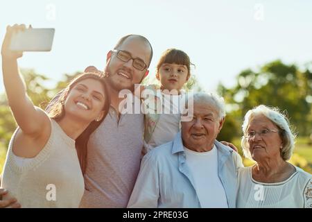 Notre peuple préféré dans le monde entier. Une famille heureuse prenant un selfie ensemble au parc. Banque D'Images