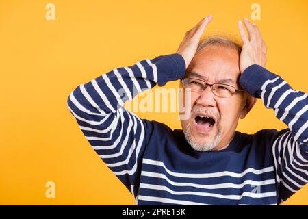 Homme asiatique aîné mains tenant la tête et les oreilles proches souffrant de maux de tête Banque D'Images