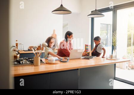 Maman aidant ses enfants avec l'apprentissage, l'éducation et le développement dans les cours en ligne à la maison. Mère, fille et fils dans la cuisine étudiant en ligne, faisant des devoirs et des mathématiques. Banque D'Images