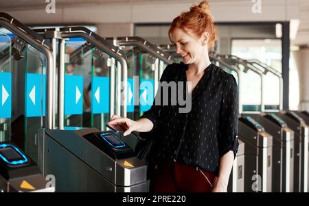 Une femme qui scanne un téléphone pour entrer dans un bâtiment moderne ou qui sécurise une entreprise à l'aide d'un lecteur sensoriel sans contact ou d'une machine. Une dame à la mode utilise une transaction de balayage rapide pour payer le billet de stationnement Banque D'Images