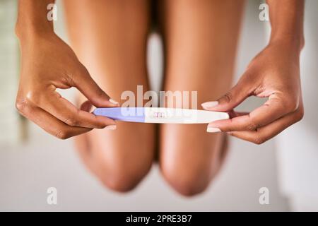 Le début d'un nouveau chapitre. Une femme qui fait un test de grossesse tout en étant assise sur les toilettes. Banque D'Images