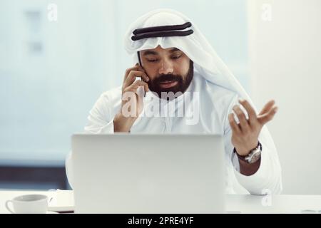 Je ne sais pas quoi vous dire... un jeune homme d'affaires habillé de vêtements traditionnels islamiques avec son téléphone portable tout en travaillant dans son bureau. Banque D'Images