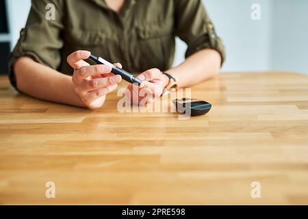 Elle a été maîtrise par ses shes. Gros plan d'une femme d'affaires non identifiable qui teste son taux de sucre dans le sang dans un bureau. Banque D'Images