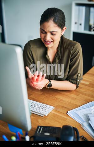 Comment ma main a-t-elle soudainement pris de la force : une jeune femme d'affaires souffrant de douleur dans la main tout en travaillant dans un bureau. Banque D'Images