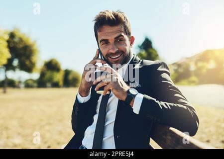 Je serai au bureau plus tard après ma pause. Un beau jeune homme d'affaires sur appel dans un parc public. Banque D'Images