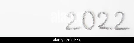 Baner Happy New Year 2022 écrit avec du papier d'aluminium et de la pluie du nouvel an sur un fond blanc isolé. Bonne année salutations. Banque D'Images