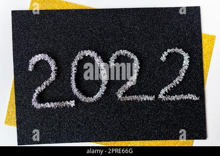L'année 2022 est écrite en tinsel d'argent du nouvel an sur fond noir. Carte de vœux. Banque D'Images