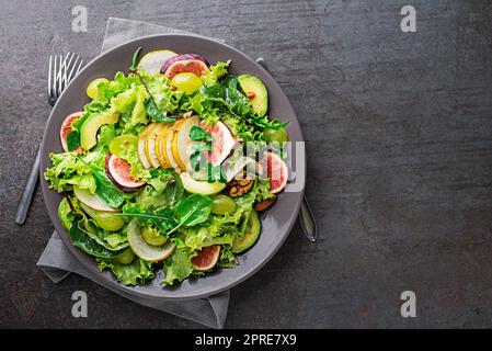 Salade verte fraîche avec fruits et noix sur fond de table gris. Concept pour un repas savoureux et sain Banque D'Images