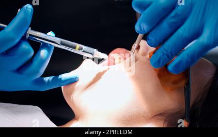 Juste un petit pincement. une femme recevant une injection au bureau des dentistes Banque D'Images