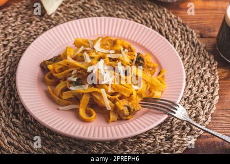 Pâtes de fettuccine avec sauce à la citrouille et champignons garnis de parmesan râpé Banque D'Images