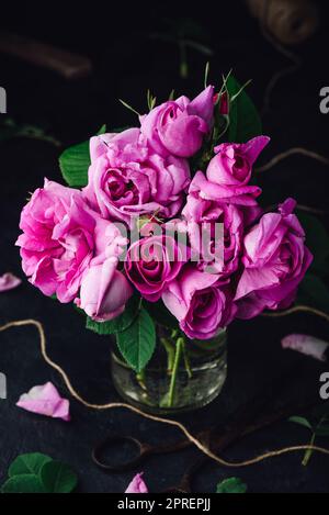 Bouquet de petites roses roses de jardin dans vase sur foncé arrière-plan Banque D'Images