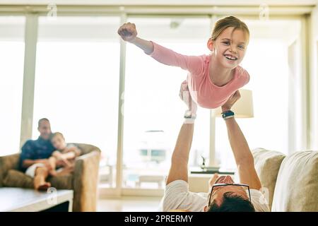 Mon père me donne l'impression d'être un super-héros. Portrait court d'une adorable petite fille jouant avec son père à la maison. Banque D'Images