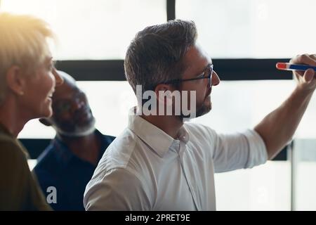 Homme d'affaires sérieux, mature et expert qui fait la présentation, la planification et la discussion dans une réunion dans une salle de réunion. Responsable effectuant un atelier de formation, enseignant et coachant les nouveaux employés pendant la conférence Banque D'Images