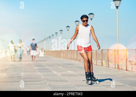 Comment j'aime rouler. Une jeune femme attrayante en rollerblading sur une promenade. Banque D'Images