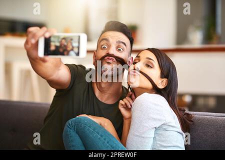 Nous sommes tombés amoureux de l'étrange l'un de l'autre. Un jeune couple prenant des selfies ensemble à la maison. Banque D'Images