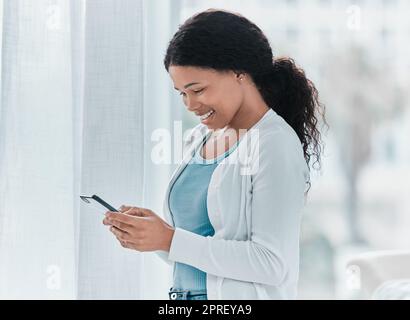 Il est plus facile de remplir les formulaires médicaux en ligne. une jeune femme attirante debout seule dans la clinique et utilisant son téléphone portable Banque D'Images