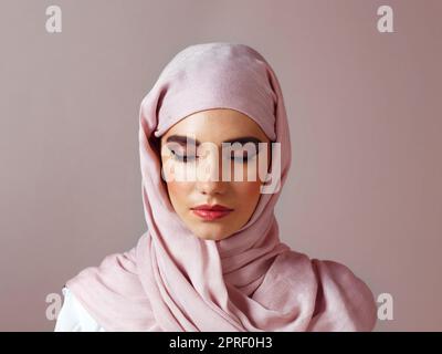 Trouver sa paix intérieure. Photo studio d'une jeune femme confiante portant un foulard coloré tout en posant sur un fond gris. Banque D'Images