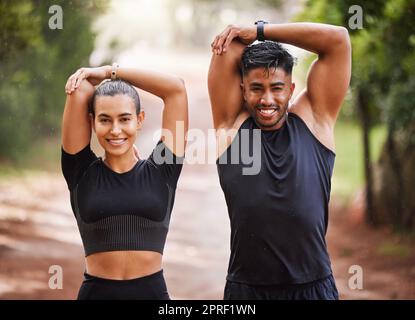 Faites équipe avec un couple ou des amis sportifs qui étirent les bras pour faire de l'exercice en plein air dans la forêt. Des partenaires d'entraînement ou des joggeurs souriants sur le point de courir ou de faire de l'entraînement cardio pour la santé et le bien-être style de vie. Banque D'Images