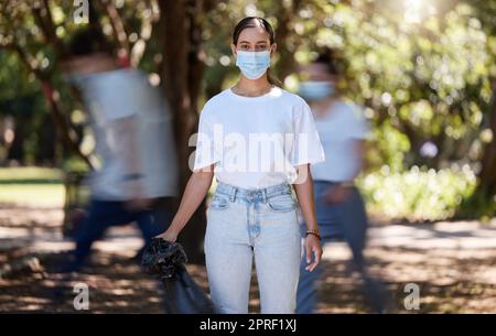 Femme en covid masque visage nettoyant le parc pour un environnement propre, hygiénique et sûr. Activiste responsable, bénévole ou travailleur de service communautaire avec des ordures, des ordures et des ordures dans un sac en plastique Banque D'Images