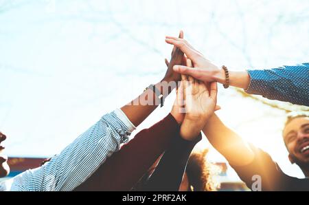 Étaient les meilleurs. Un groupe méconnaissable d'amis d'université de haut fiving en se tenant dehors. Banque D'Images