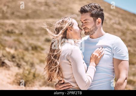 Amoureux, embrassant et liant jeune couple heureux, souriant sur une escapade de vacances à l'extérieur. Couple romantique se détendre dehors ensemble embrassant et aimant romance, bonheur et le soleil pendant une journée d'été Banque D'Images