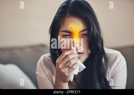 Les allergies saisonnières peuvent causer des brûlures du nez et de la congestion. Une jeune femme souffle le nez à la maison. Banque D'Images