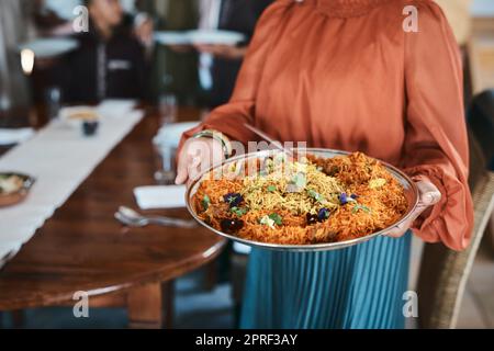 Nourriture, dîner et consommables avec un plat de paella traditionnel dans les mains d'une femme à la maison. Gros plan d'un bol de fruits de mer espagnols, prêt à servir et à nourrir la famille affamée pour le déjeuner ou un dîner sain Banque D'Images