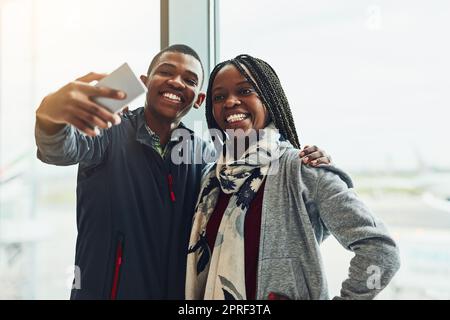 Eh bien, il faut tout documenter sur notre voyage. Deux jeunes qui prennent un selfie ensemble à l'aéroport. Banque D'Images