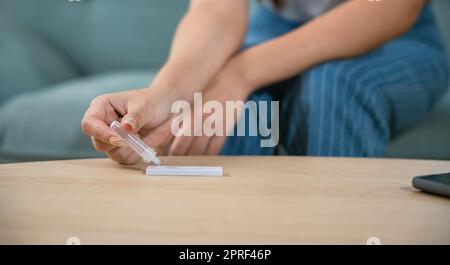 Rapprochez-vous des mains de la femme à l'aide d'un kit de test d'antigène rapide pour l'auto-test Banque D'Images