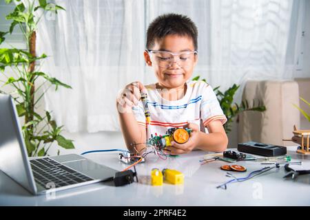 Enfant asiatique assemblant le projet de travail de robot de voiture Arduino à la maison Banque D'Images