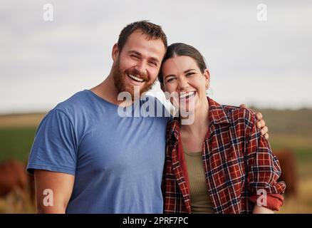 Couple fermier heureux, insouciant et excité debout à l'extérieur sur des terres de bétail ou de bétail. Portrait des amoureux détendus se reposant sur des terres biologiques ou durables souriant et appréciant la nature Banque D'Images