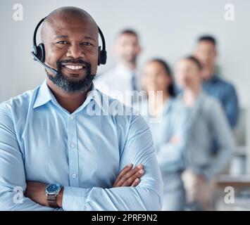 Établir des relations de confiance et durables avec les clients. Portrait d'un agent de centre d'appels mature debout dans un bureau avec ses collègues dans le b Banque D'Images