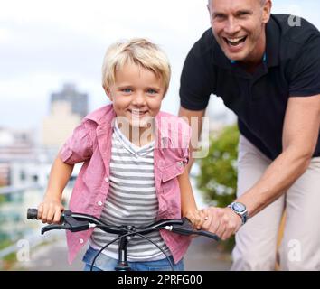 Moments spéciaux pour le père et le fils. Un père heureux enseignant à son fils comment faire un vélo Banque D'Images