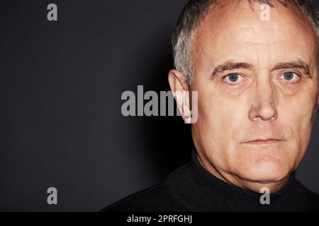 Il prend la vie très au sérieux. Studio portrait d'un homme mature isolé sur noir Banque D'Images