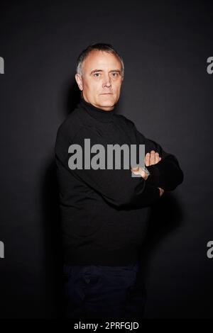 HES naturellement confiant. Studio portrait d'un homme mature isolé sur noir Banque D'Images