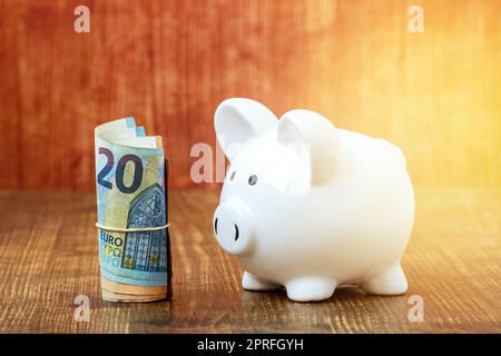 Billets en euros, cash roll à côté de la banque de porc blanche Banque D'Images