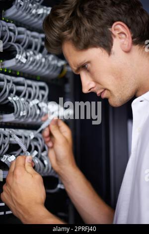 Prêt à vous remettre en ligne. Un technicien informatique qui connecte les câbles Banque D'Images