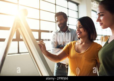 Mettre certaines de leurs plus grandes idées en perspective. Un groupe de gens d'affaires brainstorming ensemble dans un bureau. Banque D'Images