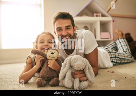 Elle signifie le monde pour moi. Portrait d'un beau jeune homme et de sa fille jouant avec des jouets en peluche sur le plancher de sa chambre. Banque D'Images