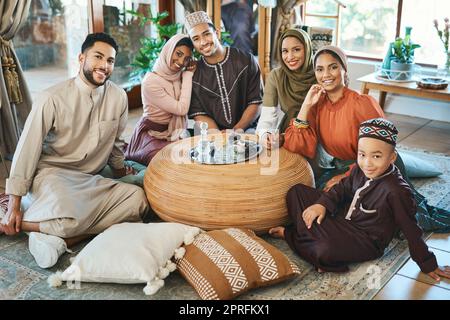 Bonne famille musulmane célébrant le ramadan ensemble, souriant et solidaire dans le salon. Des parents détendus passent la journée à passer des vacances religieuses. Les frères et sœurs islamiques se réunissent dans leur maison familiale Banque D'Images