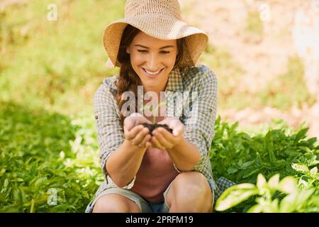 Une nouvelle vie est belle à voir. Un jeune agriculteur heureux tenant une pile de terre avec une plantule qui en sort. Banque D'Images