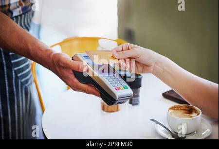 Payer est aussi simple qu'un robinet. Une jeune femme non identifiable utilisant sa carte de crédit pour payer pour le café dans un café. Banque D'Images